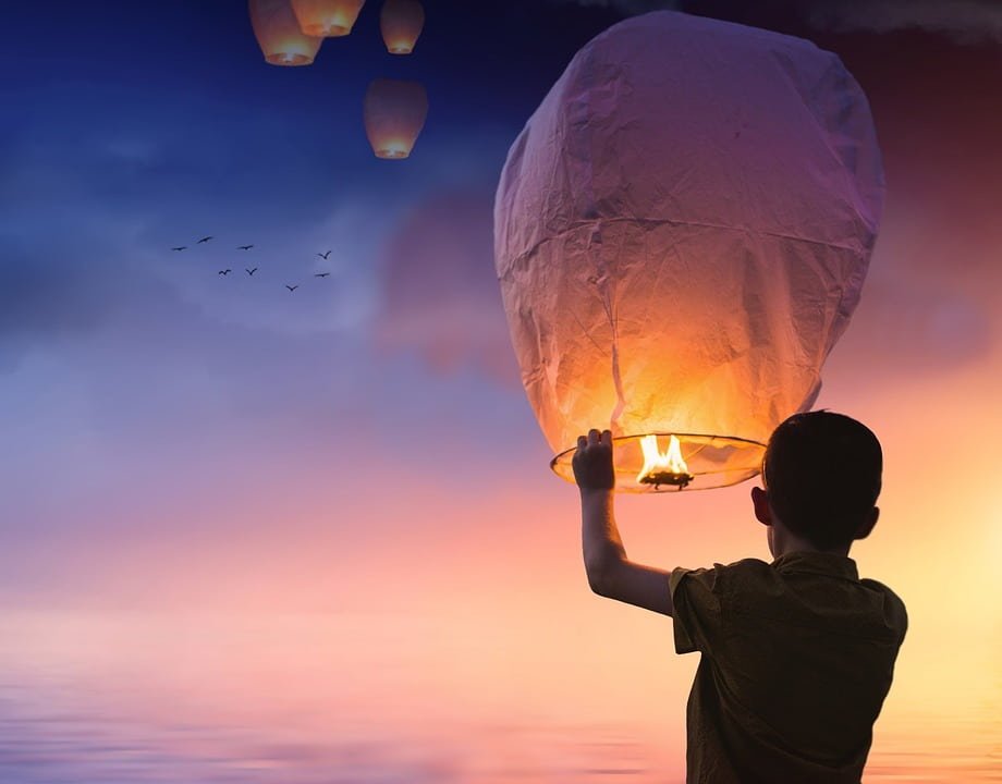 boy launching small hot air baloon