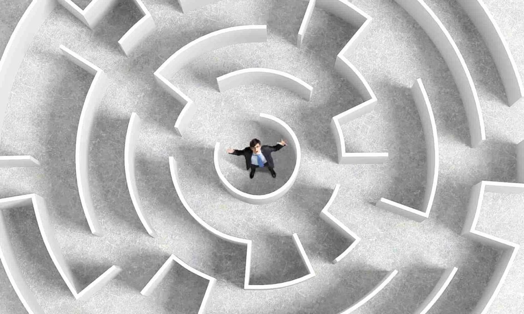 business man at the center of a maze looking frustrated